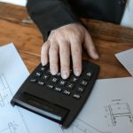 человек рассчитывает бюджет на калькуляторе