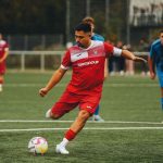 футболист делает удар по мячу на поле